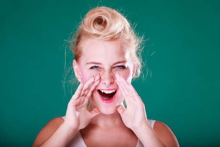 Yelling gestures concept. Lovely pin up girl screaming with hands close to mouth. Studio shot on green backgroundの写真素材