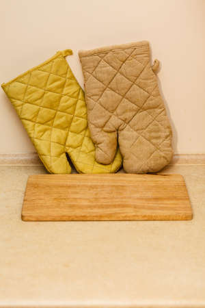 Home interior objects concept. Detailed closeup of old fashioned wooden kitchen board and glovesの写真素材