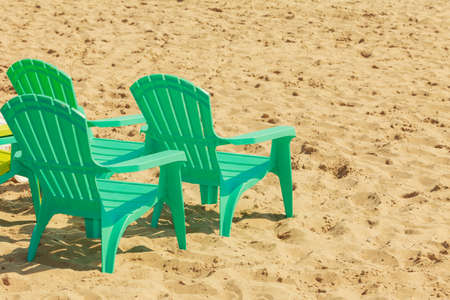 Rest and relax in summer. Three green plastic chairs on sand. Relaxation place on sunny beach.の写真素材