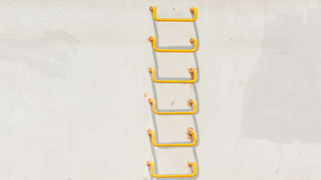 Simple objects pictures concept. Minimalist shot of yellow ladder on light grey conrecete wallの写真素材
