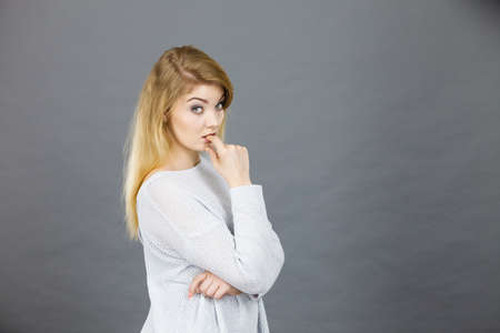 Blonde attractive woman contemplating thinking about something having worried face expression gesturing with hands.の写真素材