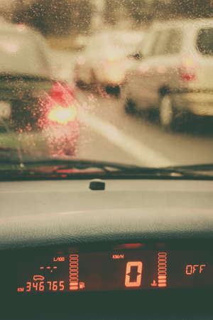 Shot inside car during driving through city streets on cloudy, rainy autumnal day. Traffic lights and vehicles.の写真素材
