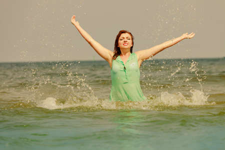 Summer fun, recreation outside concept. Redhead adult woman playing in water during summertime, having great time and smiling joyfullyの写真素材
