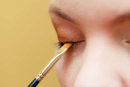 Visage concept. Close up woman getting make up on eyelids. Applying eyeshadow with brush, closed eyes.の写真素材