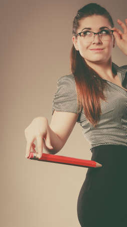 Teacher looking elegant woman wearing dark tight skirt, shirt and eyeglasses holding big oversized pencilの写真素材