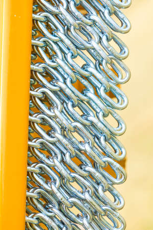 Abstract metal concept. Detailed closeup, lot of silver chains on yellow agriculture machinery