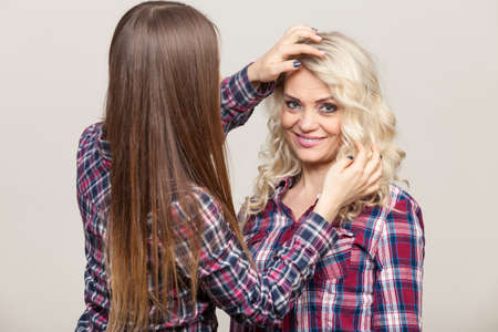 Generation and relationship. Adult daughter with mother. Two gorgeous casual style women long hair blonde mom and brown haired girl, studio shotの写真素材