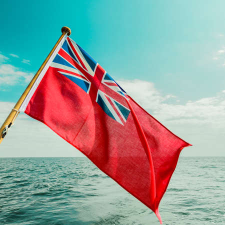 The uk red ensign the british maritime flag flown from yacht sail boat, blue sky and baltic sea. Summer and travel voyageの写真素材