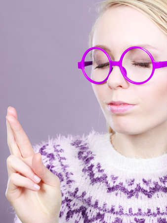 Gestures and signs concept. Teenage blonde woman making promise gesture with fingers crossed.の写真素材