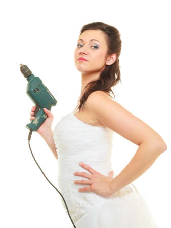 Taking care of house, sharing duties concept. Bride in wedding dress holding drillの写真素材