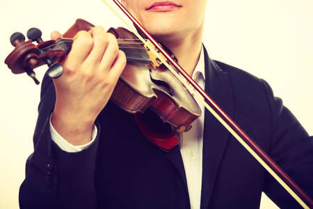 Music passion, hobby concept. Close up young man man dressed elegantly playing on wooden violin. Studio shot on white backgroundの写真素材