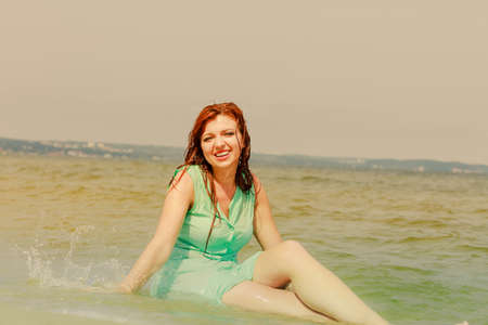 Summer fun, recreation outside concept. Redhead adult woman posing in water during summertime, having great time.の写真素材