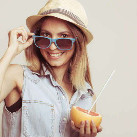Happy glad woman tourist wearing straw hat and sunglasses holding grapefruit citrus fruit. Healthy diet food. Summer vacation holidays concept.の写真素材
