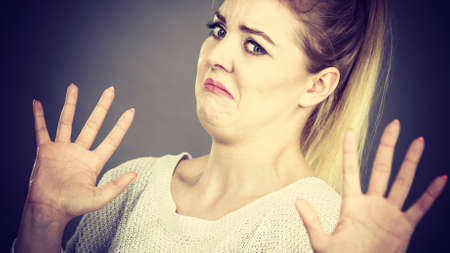 Scared woman gesturing stop gesture with hands seeing something unpleasant or scary.の写真素材