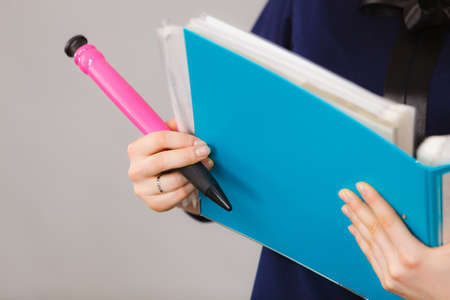 Woman hand holding blue binder with many documents and pen. Office, bookkeeping objects concept.の写真素材