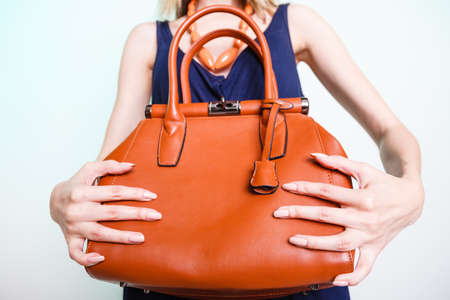 Woman holding brown leather handbag. Stylish girl showing bag. Female fashion vogue. Studio shotの写真素材
