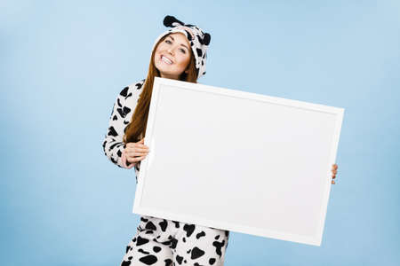 Smiling teenage girl in funny nightclothes, pajamas cartoon style with blank empty banner board. Advertisement copyspace.の写真素材