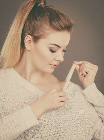 Woman holding her bra strap from under her sweater. Brafitting concept. Grey background.の写真素材