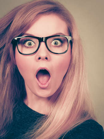Astonished or surprised woman in big nerd eyeglasses having shocked face expressionの写真素材