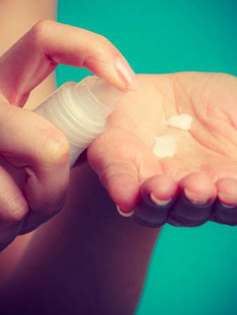 Beauty, cosmetics, concept. Woman applying white moisturizing cream from bottle with pump on hand to test productの写真素材
