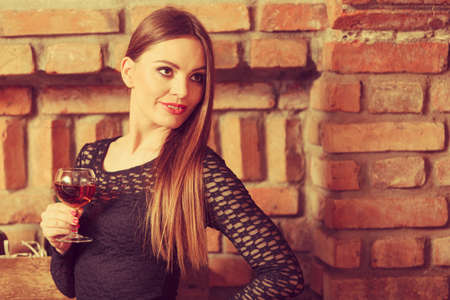 Elegant beauty lady long hair full make up wearing black dress tasting wine in rural cottage interior cellerの写真素材