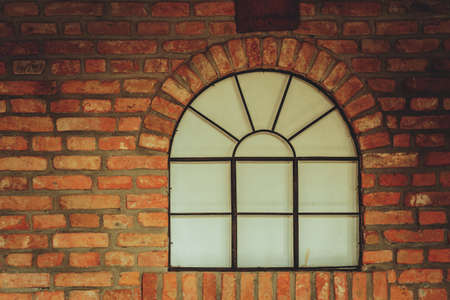 Textures and close up detailed patterns concept. Big rounded window on red brick wallの写真素材