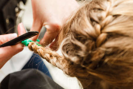 Kids hairstyles and haircare concept. Blonde toddler girl getting her braided hairstyle done at hairdresserの写真素材