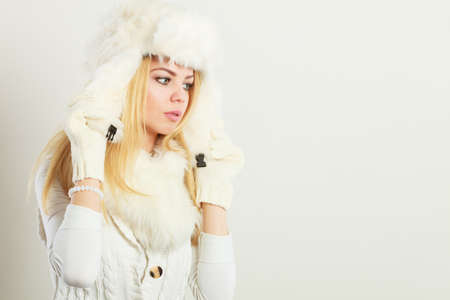 Winter clothing, people, fashion concept. Blonde woman with fur cap. Attractive lady has white...