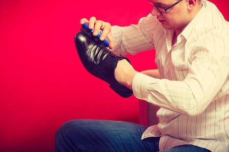 Footwear and man fashion, gentleman outfit concept. Guy cleaning and polishing black elegant shoesの写真素材