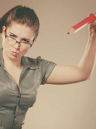 Mobbing at work, bad job relations concept. Angry mad bossy businesswoman being furious holding big pencilの写真素材