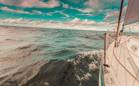 Yachting on sail boat bow stern shot splashing sea water. Sporty transportation conept.