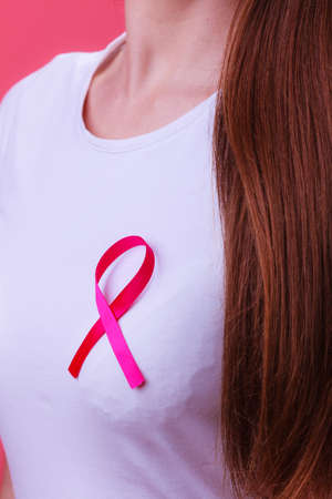 Healthcare, medicine and breast cancer awareness concept - Closeup of pink badge ribbon on woman chest to support breast cancer causeの写真素材