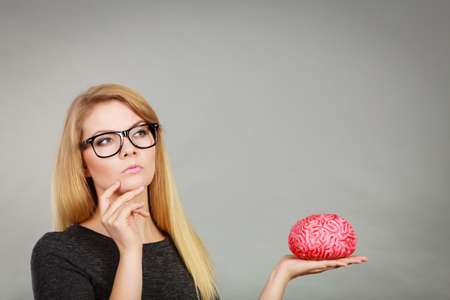 Intellectual expressions, being focused concept. Closeup of attractive woman thinking face expression holding brainの写真素材