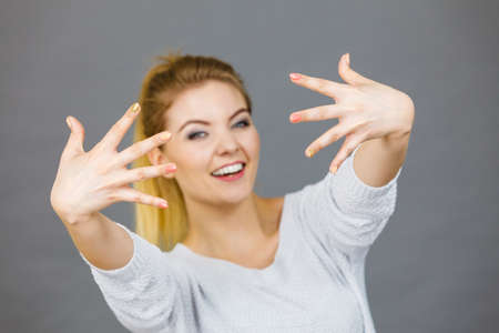 Happy proud young woman showing her hands in front of her face, studio shot grey background.の写真素材