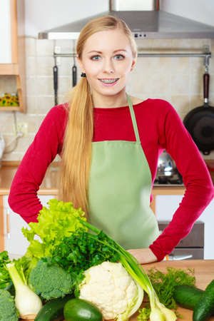 Young woman in kitchen having many green vegetables about to cook something healthy and vegetarianの写真素材