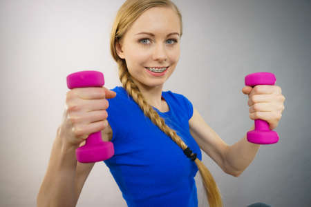 Teenage young woman working out at home with small light dumbbells. Training at home, being fit and...