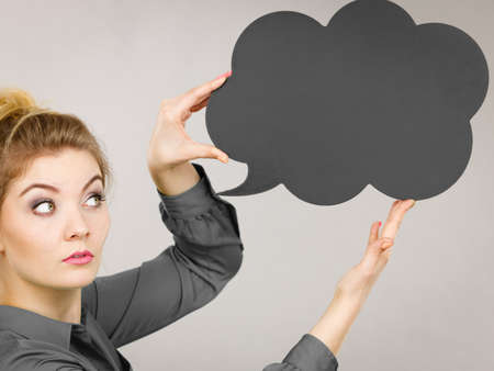 Serious student looking woman wearing grey shirt holding black thinking bubble