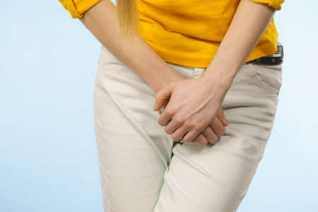 Closeup young sick woman with hands holding pressing her crotch lower abdomen. Medical or...