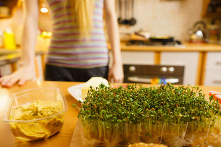 Cuckooflower on wooden kitchen table. Woman making delicious vegetarian sandwich.の写真素材