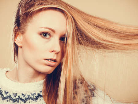 Haircare, choosing best conditioner for tangled hairstyle concept. Teenage blonde girl brushing her hair with combの写真素材