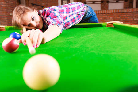 Play and fun concept. Young happy girl having fun with billiard. Smiling fashionable woman playing...