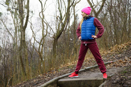 Outdoor sport exercises, sporty outfit ideas. Woman wearing warm sportswear training exercising...