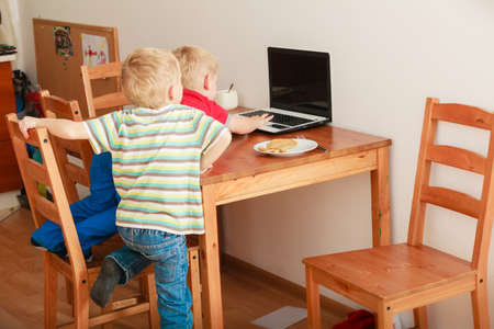Children and technology, spending free time online concept. Two boys using laptop computer playing...