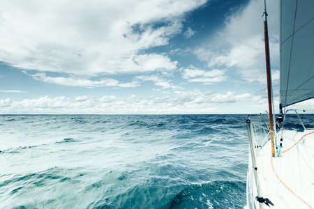 Yachting on sail boat during sunny summer weather on calm blue sea water. Sporty transportation conept.の写真素材