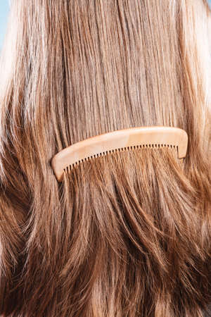 Haircare concept. Straight brown hair with wooden comb closeupの写真素材