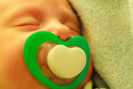 Infant care, beauty of childhood concept. Little newborn baby sleeping calmly in bed with teat in mouth.の写真素材