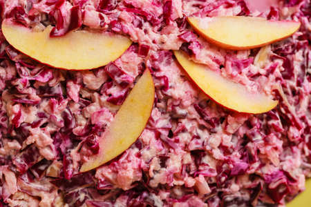 Detailed closeup of salad made of red cabbage decorated with apple slicesの写真素材