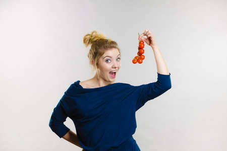 Organic vegetables and food concept. Happy positive smiling woman holding fresh cherry tomatoesの写真素材