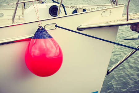 Yachting, sailing conept. Sailboat in the sea with many red fenders buoy.の写真素材