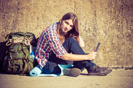 Man tourist backpacker relaxing outdoor sitting by grunge wall using tablet. Internet, tourism...